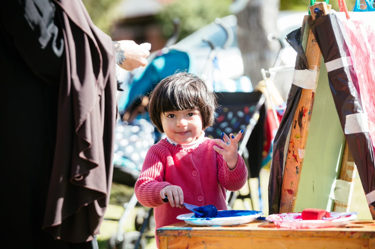child holding paint roller and blue paint tray