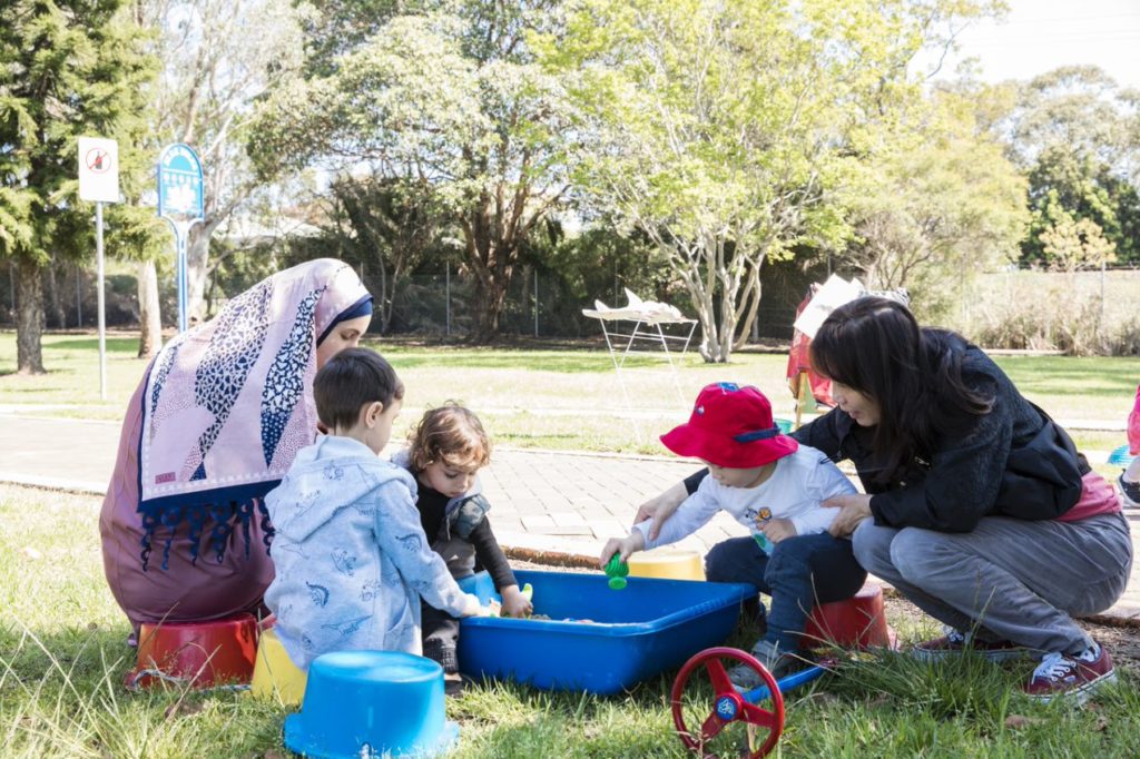 young children with adults playing in park