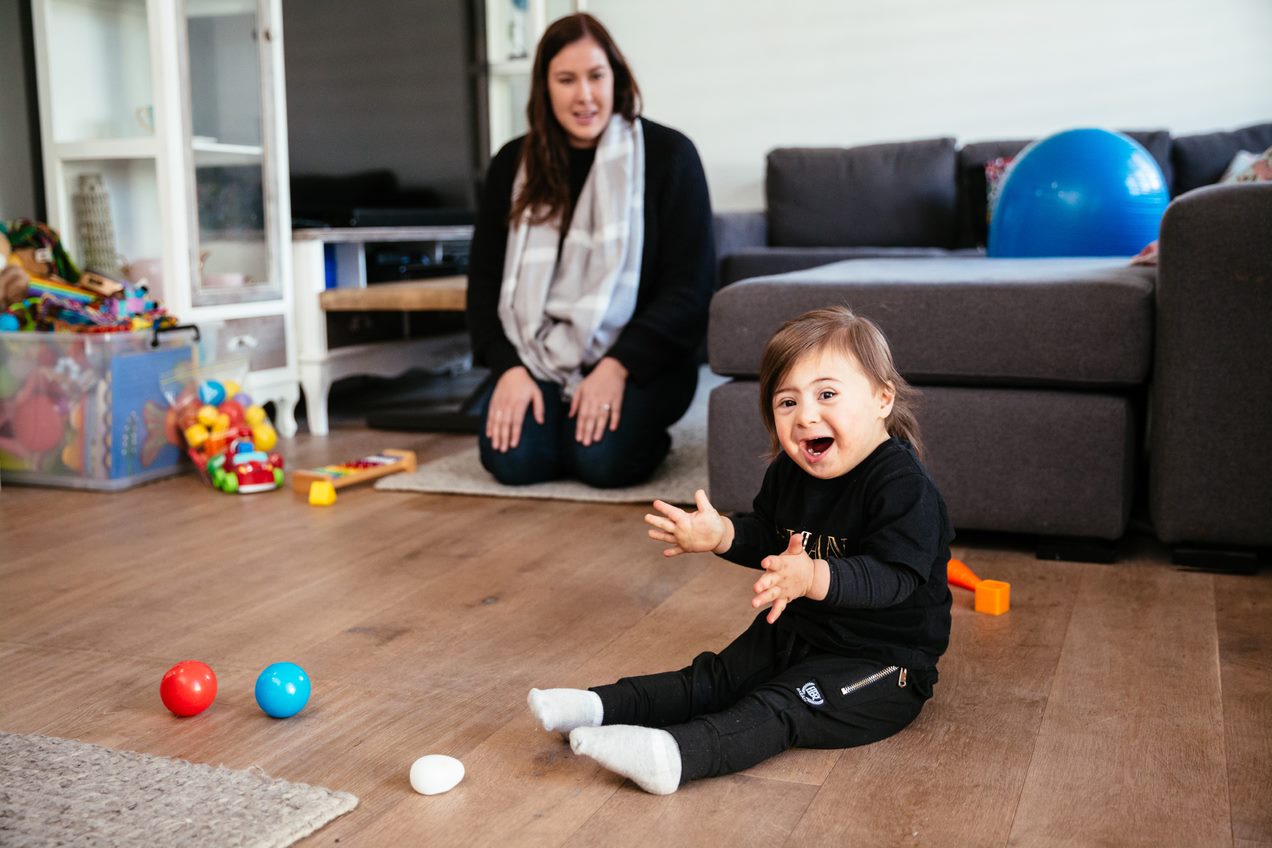 young child sitting on floor with woman sitting near couch